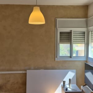 קיר צבוע עם חלון ומנורה תלויה