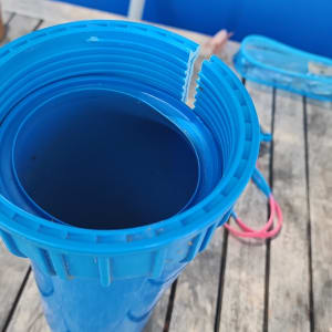 מיכל פלסטיק כחול עם הברגה על שולחן עץ