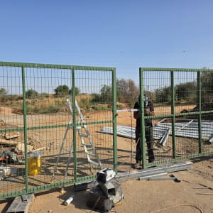 שער מתכת ירוק עם אדם עובד בשטח פתוח