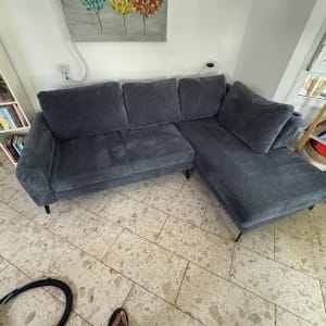 ספה אפורה עם שואב אבק על הרצפה