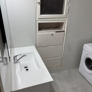 חדר אמבטיה עם כיור, ארון ומכונת כביסה