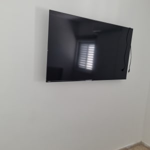 טלוויזיה תלויה על הקיר עם כבלים חשמליים