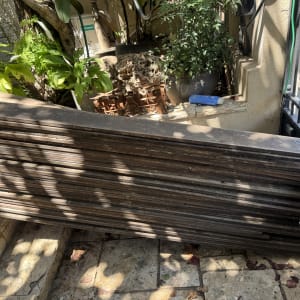 ערימת קרשים ליד צמחים וגדר מתכת