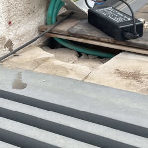 חיבורי חשמל ושנאי לצד צנרת שרשורית מתחת לאריח שבור