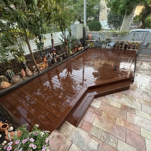 דק עץ בגינה עם עציצים ופרחים מסביב