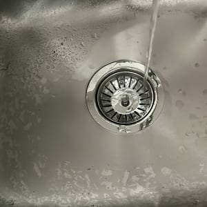 מים זורמים בכיור נירוסטה עם מסנן