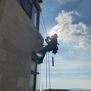 אדם תלוי על חבלים ליד קיר בניין