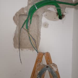 חוטי חשמל ירוקים וצהובים בקיר עם סולם עץ