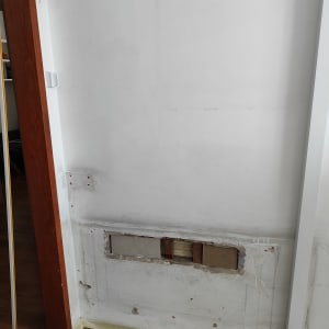 קיר לבן עם חור ותיקונים, דלי צבע ירוק