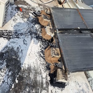 חומר איטום שחור נמרח על גג ליד קולטים