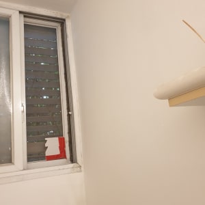 קיר צבוע בלבן ליד חלון עם תריסים