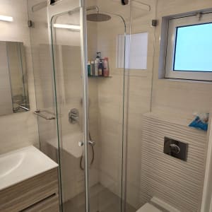 מקלחון זכוכית עם ראש מקלחת ומדף סבונים