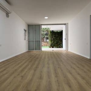 חדר ריק עם רצפת עץ ותריסים בחלון