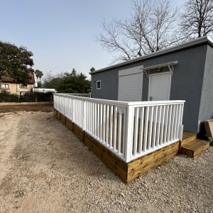 מבנה עץ עם מעקה לבן בחצר