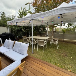 אוהל לבן עם שולחנות וכיסאות בגינה לאירועים