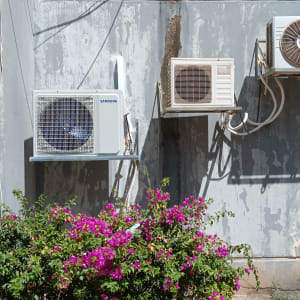שלוש יחידות חיצוניות של מזגנים מותקנות על קיר חיצוני.