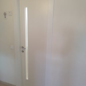 דלת לבנה עם חלון צר וידית מתכת