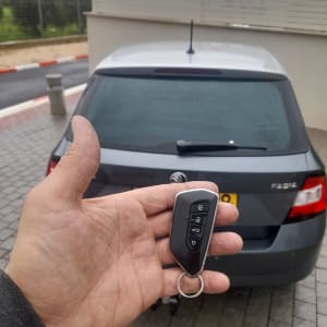 מפתח רכב חכם ביד מול רכב חונה