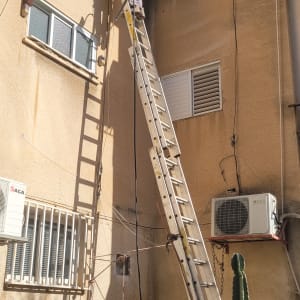 אדם על סולם גבוה ליד קיר בניין