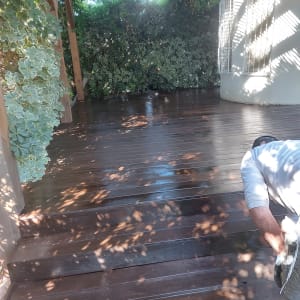 אדם צובע דק עץ בחוץ עם מברשת