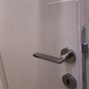 ידית דלת מתכתית על דלת לבנה