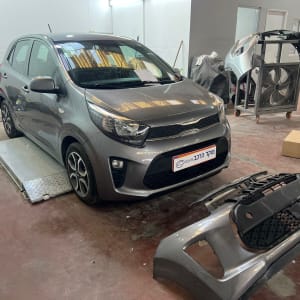 רכב אפור במוסך עם פגוש מפורק על הרצפה