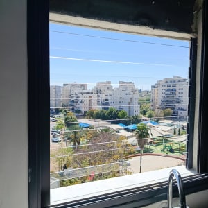 נוף עירוני מבעד לחלון עם נוף לבניינים וגינה ציבורית