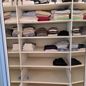 ארון בגדים עם מדפים מסודרים, בגדים מקופלים.