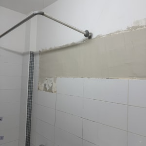 קיר אמבטיה עם אריחים וצינור מקלחת מותקן