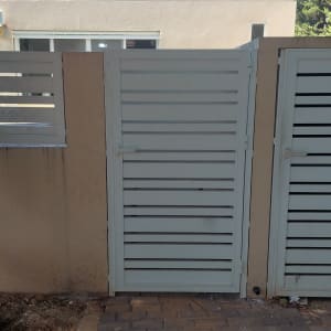 שער אלומיניום ליד בית עם שביל מרוצף