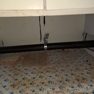 צינור שחור מתחת לכיור עם תושבת מתכת