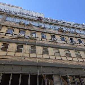 אדם עובד בגובה על בניין עם חבלי בטיחות