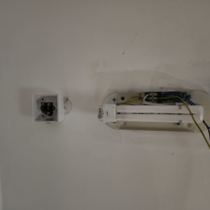 חוטי חשמל מחוברים למנורת פלורסנט על קיר