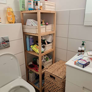 מדפים עם מוצרי טיפוח וסל כביסה בחדר אמבטיה