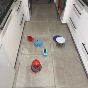 כלים על רצפת מטבח, דליים ומיכלים שונים.