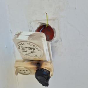 שקע חשמלי עם חוטים חשופים בקיר