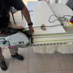 אדם חותך דלת עם מסור חשמלי על שולחן עבודה