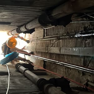 אדם עם קסדה עובד בצינורות במנהרה צרה