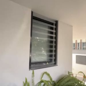 חלון עם תריסים על קיר חיצוני ליד צמחייה