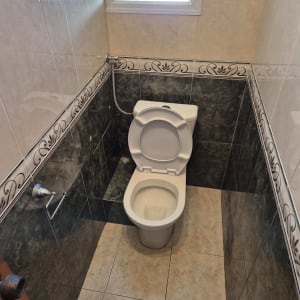 אסלה לבנה בחדר שירותים עם אריחים כהים