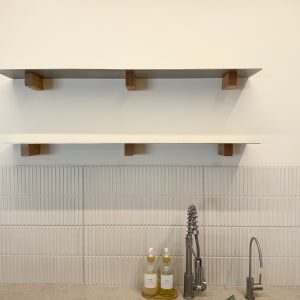 מדף עץ מעל כיור עם ברזים ובקבוקי סבון