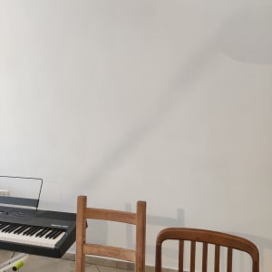 קיר לבן עם צל של מנורה קלועה