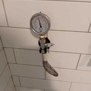 מד לחץ מחובר לצינור גמיש על קיר אריחים