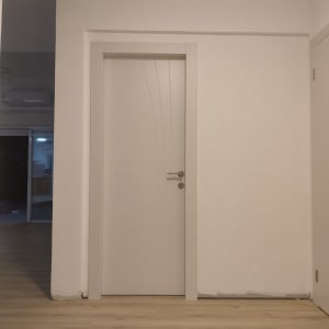 דלת לבנה עם ידית מתכת על רקע קיר לבן