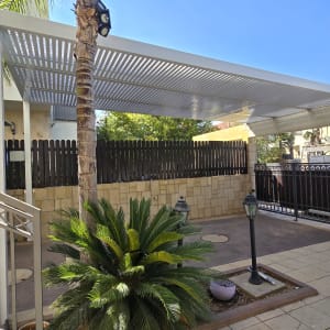 פרגולה מאלומיניום עם קורות אופקיות בחצר