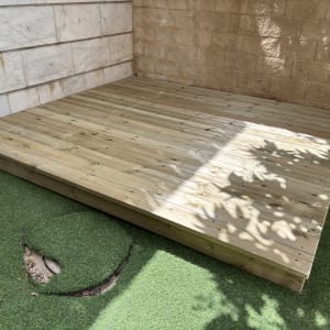 פלטפורמת עץ בגינה עם דשא סינתטי מסביב