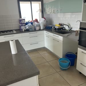 מטבח עם מוצרי ניקיון ודלי על הרצפה
