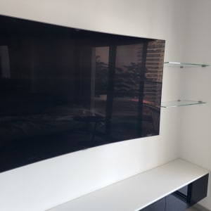 מדף זכוכית ליד טלוויזיה על קיר לבן