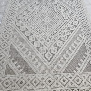 שטיח עם דוגמה גיאומטרית על רצפה אפורה