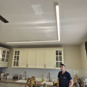 חשמלאי עומד ליד סולם במטבח עם תאורה מותקנת